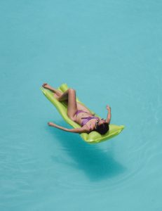 Person laying on inflatable mattress in a swimming pool