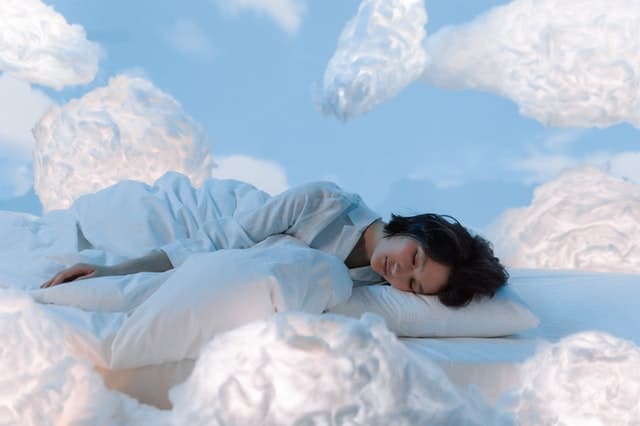 Person Sleeping On Bed Surrounded In Clouds