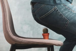 Person nearly sitting on a small cactus, signifying pain from hemorrhoids