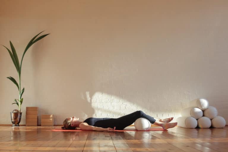 Lady doing yoga with a yoga bolster under her knees