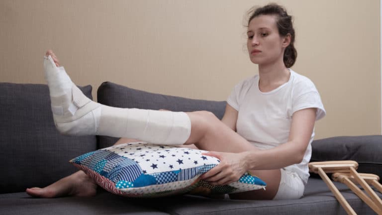 Lady with injured leg in cast trying to elevate legs with a pillow