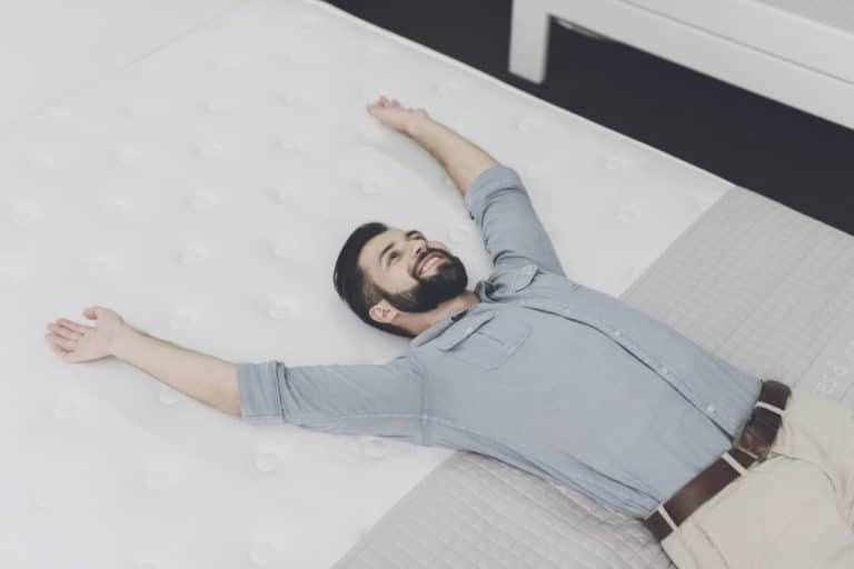 man laying on a mattress with arms up
