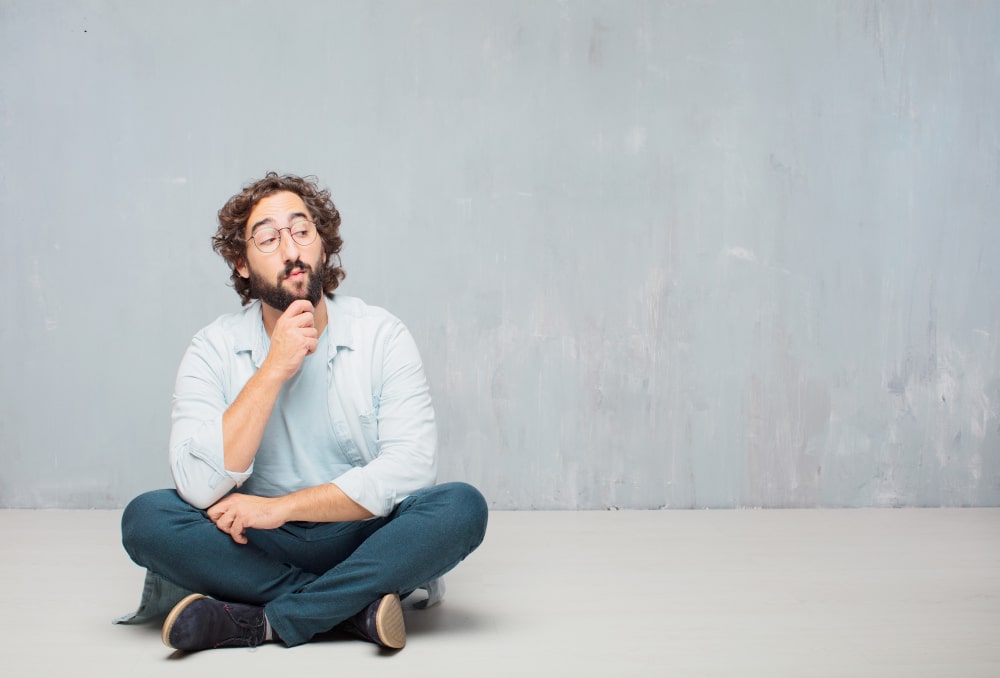 Man sitting on floor thinking seriously